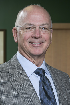 A man in a suit and tie smiling for the camera.